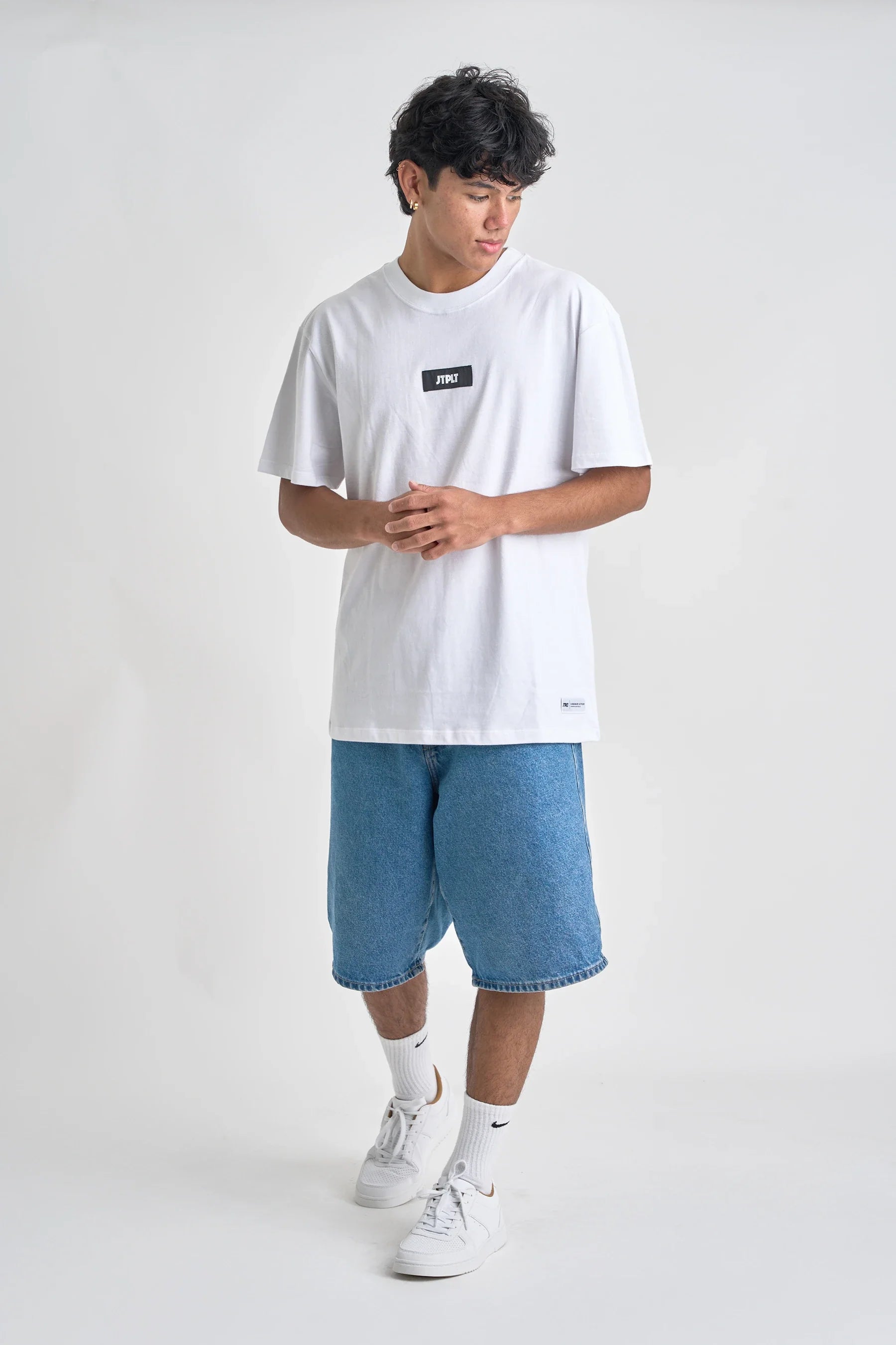 Person wearing a white t-shirt and blue shorts on a white background
