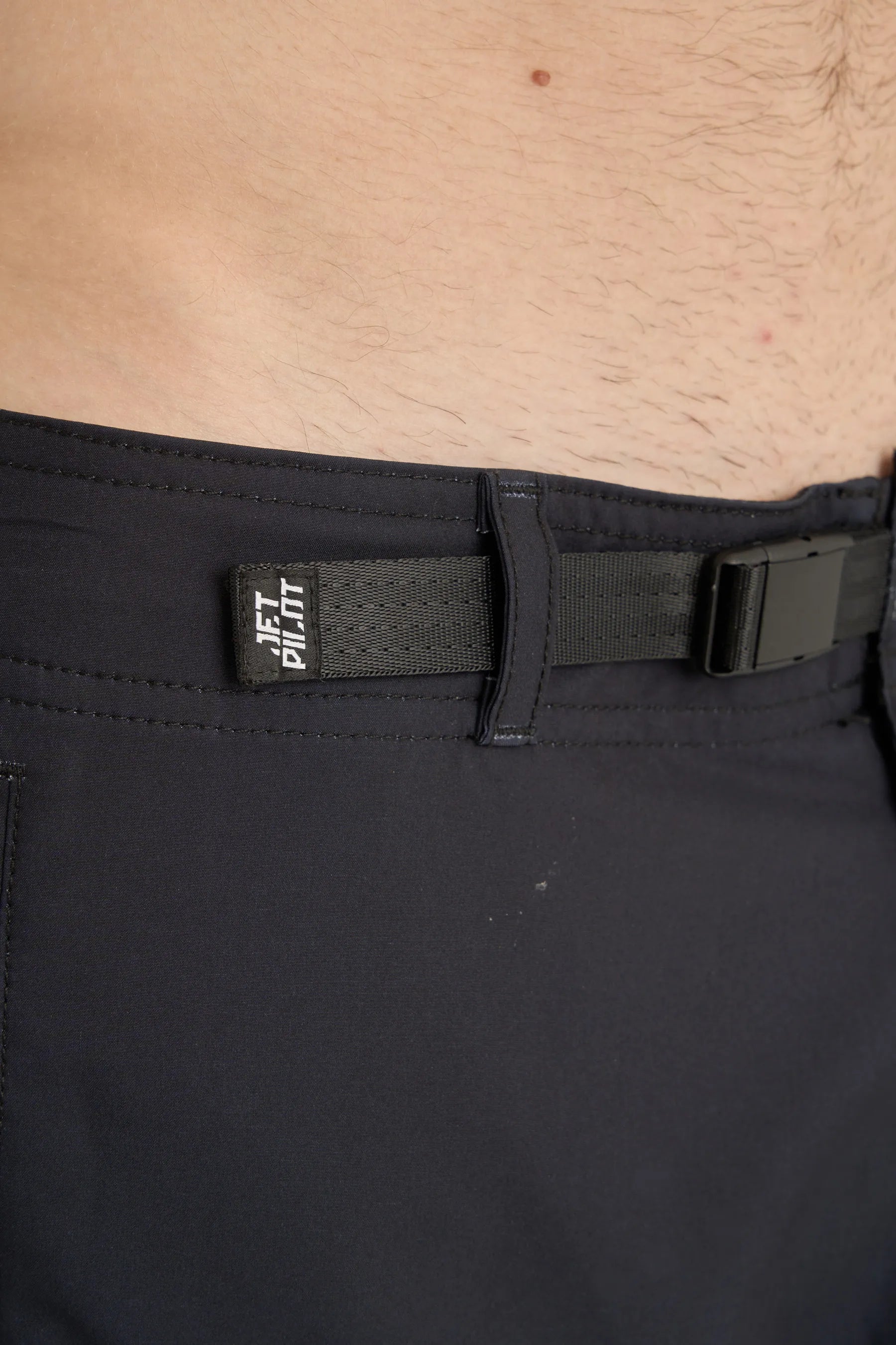 Black pants with a belt and visible brand logo on a beige background