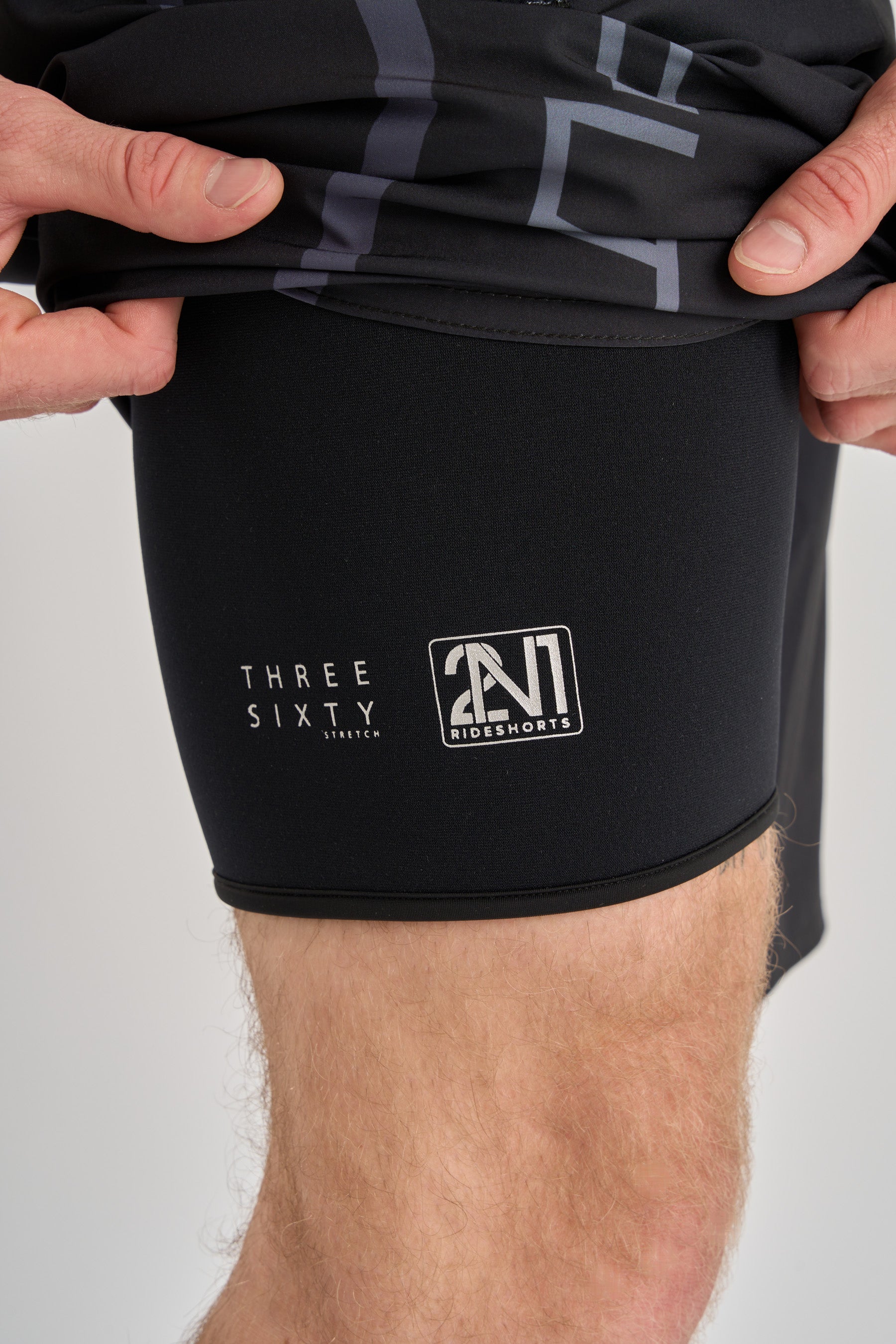 Black boardshorts shorts with neoprene liner legging, visible branding on a plain background