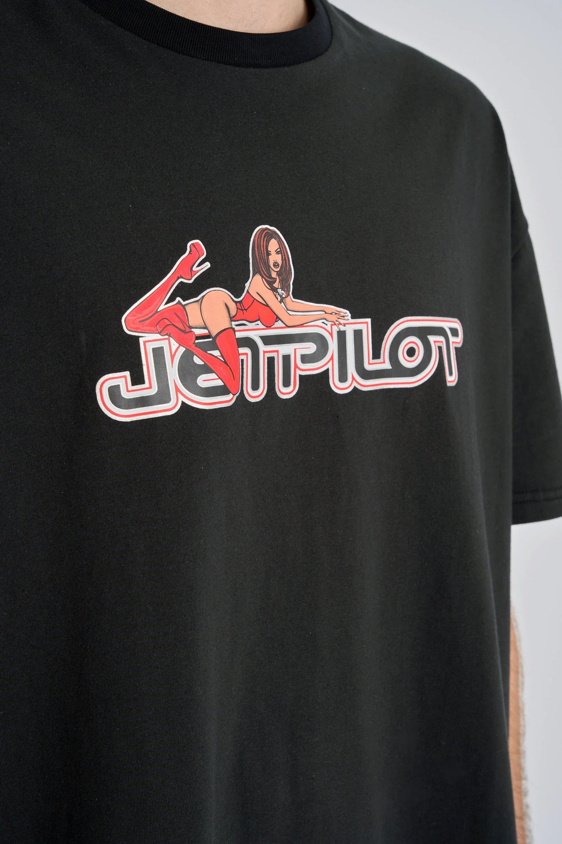 Black t-shirt with a graphic design featuring a woman lying on the logo 'JETPILOT' on a plain background