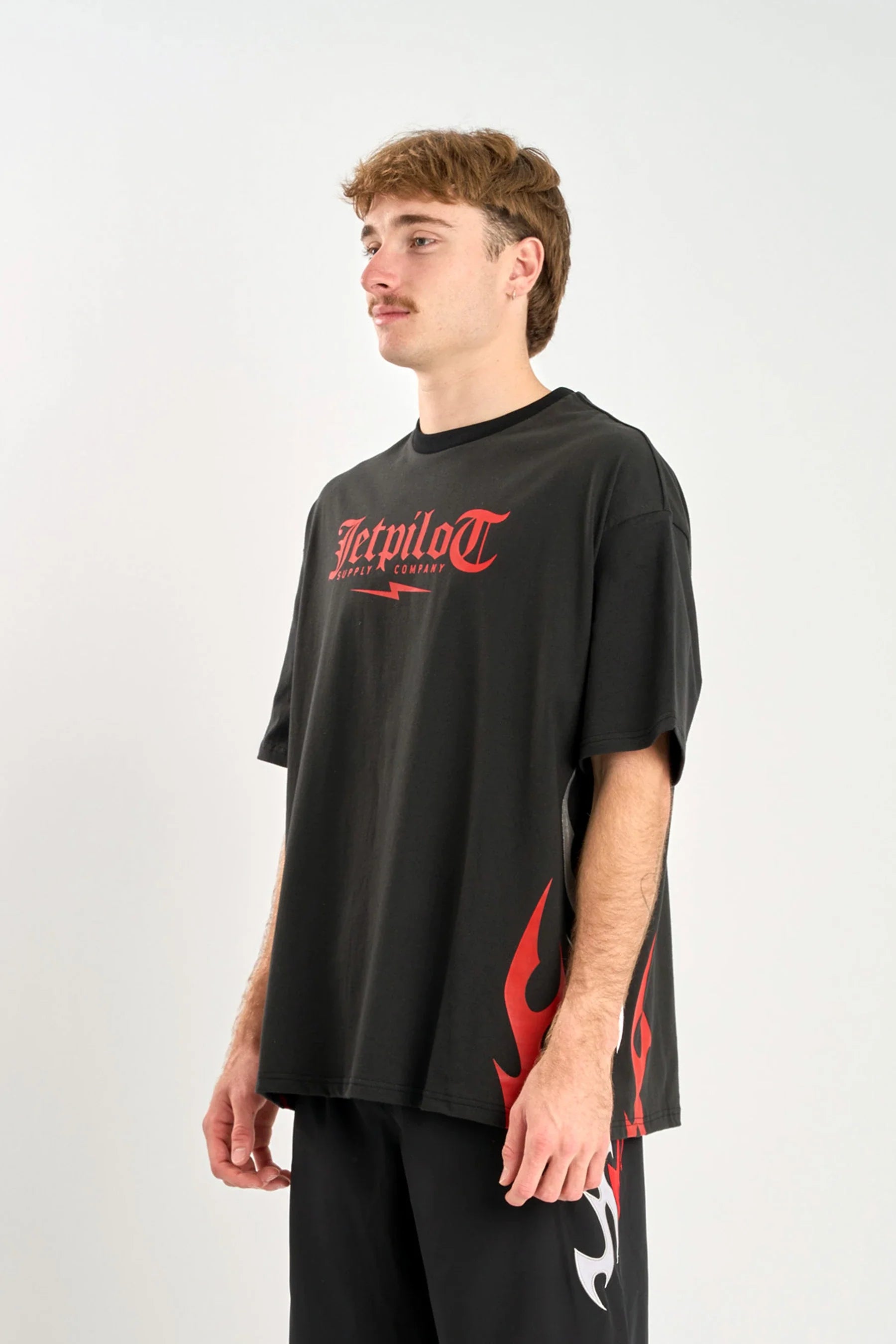 Person wearing a black t-shirt with red graphics and text on a white background