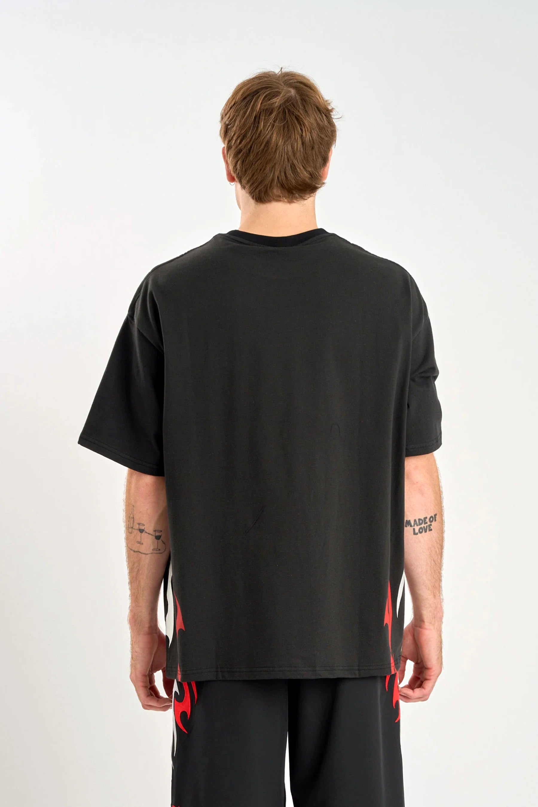 Back view of a person wearing a Jetpilot Tribal Heavy Tee - Black with red/grey accents around the bottom of the shirt on a white background