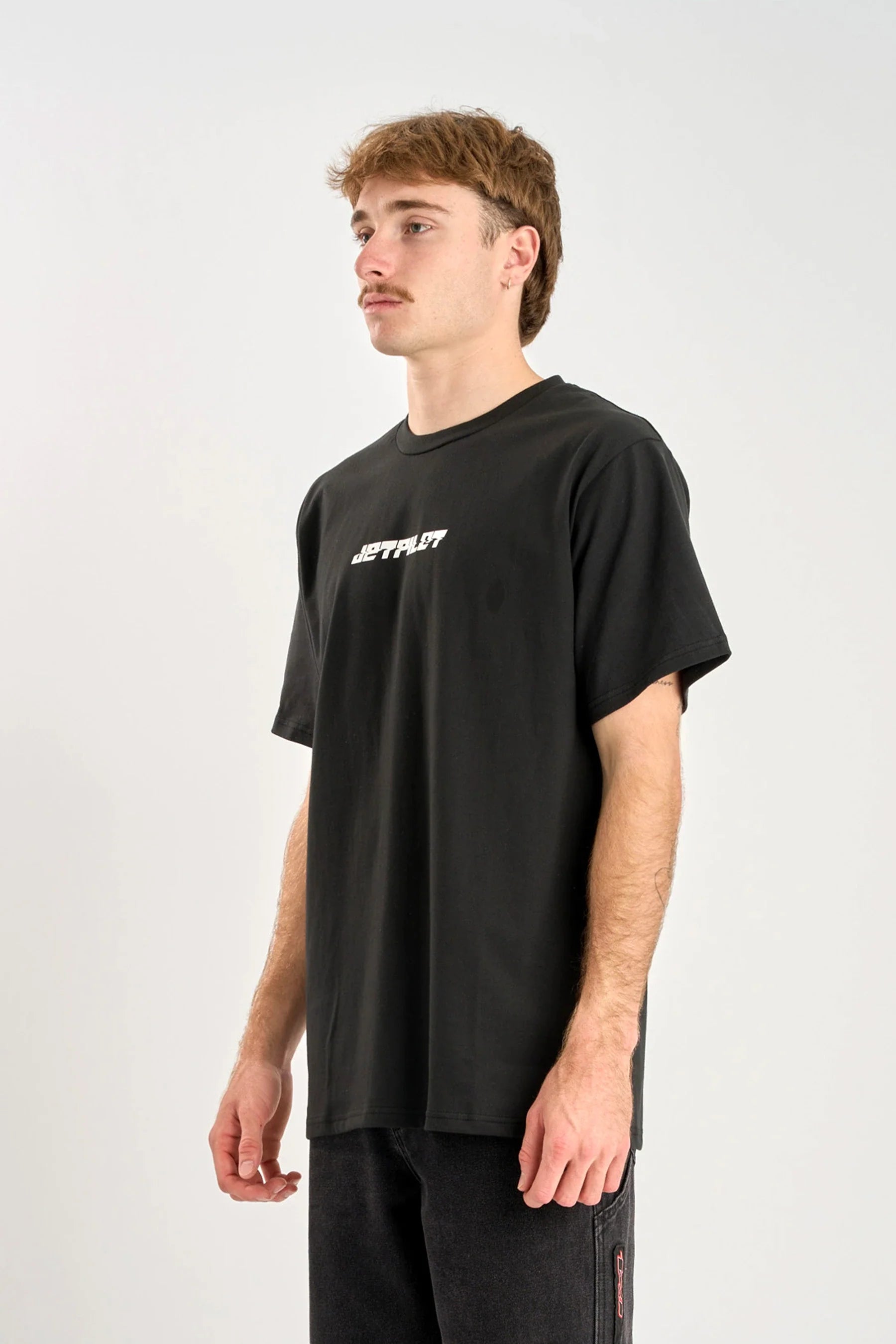 Person wearing a black Jetpilot Progressive t-shirt with white text on a white background