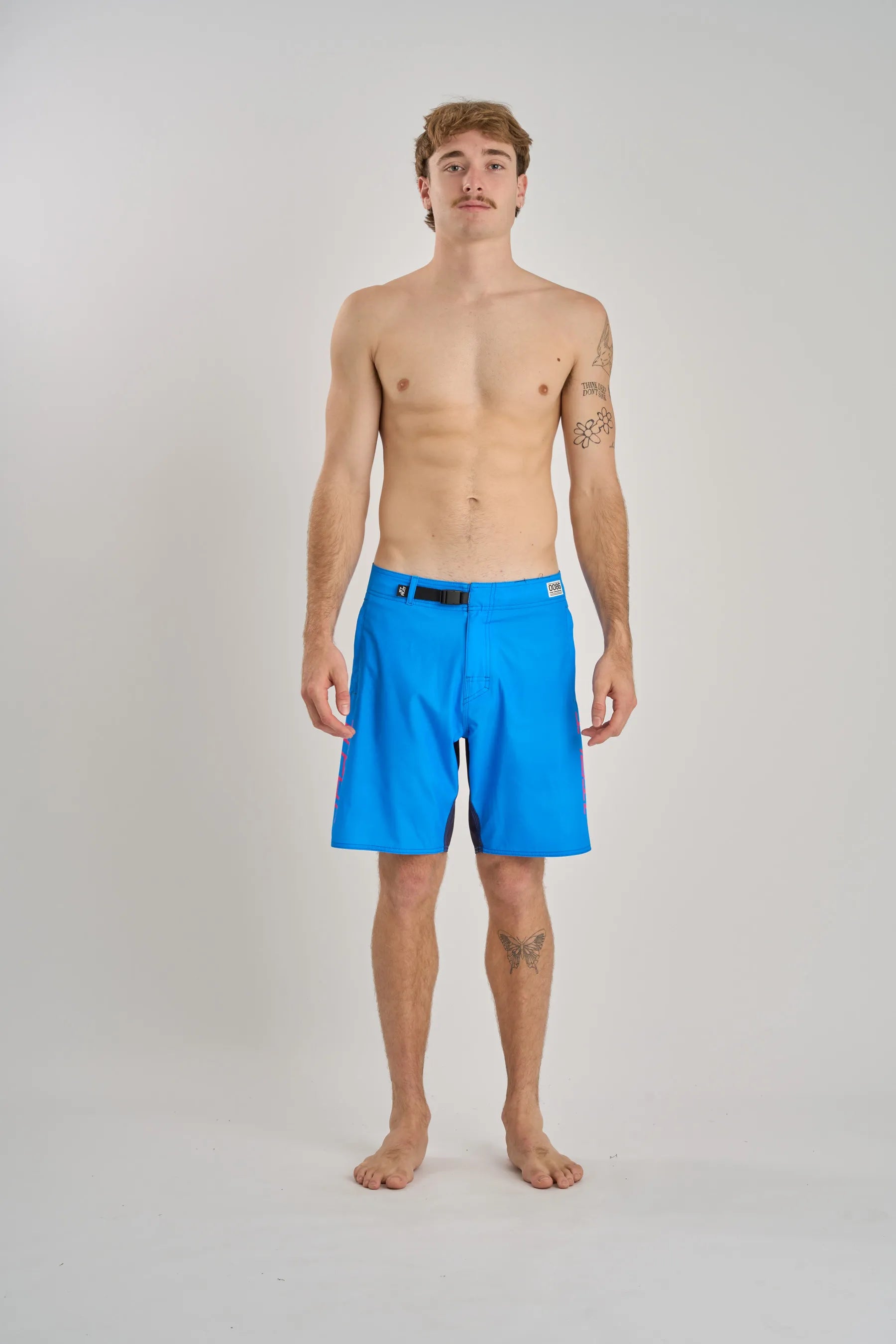 Man wearing bright blue boardshorts on a plain background