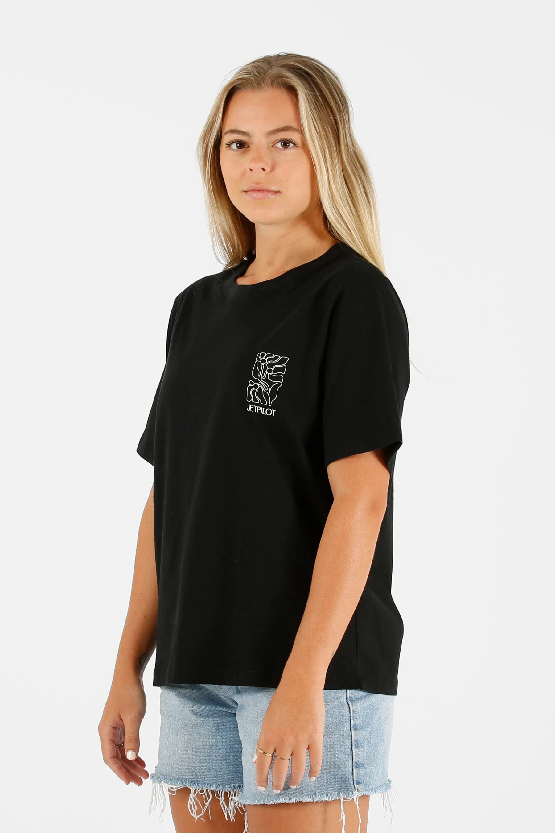 Person wearing a black Jetpilot Luna t-shirt with a graphic design on a white background