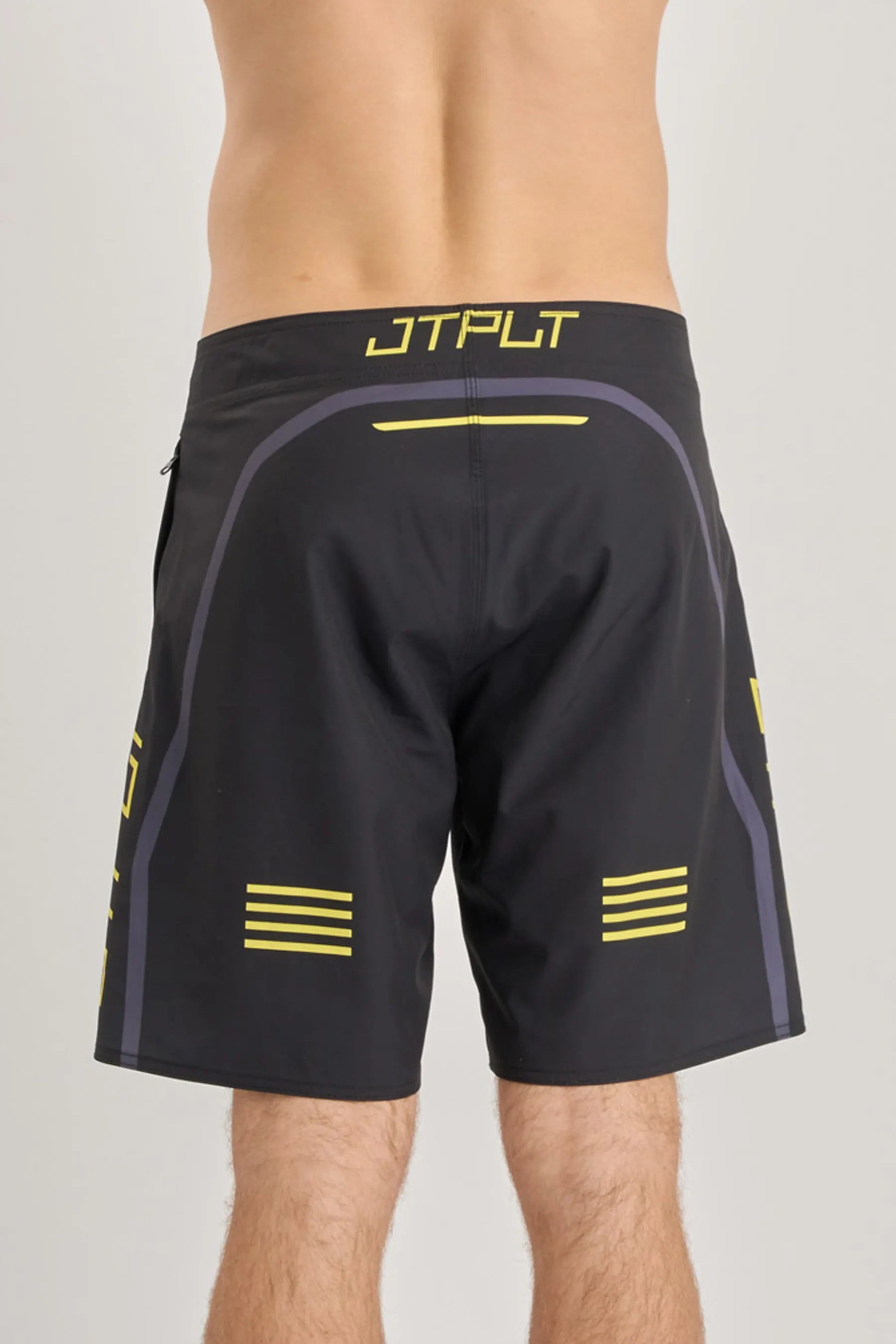 Black board shorts with yellow accents and branding on a grey background
