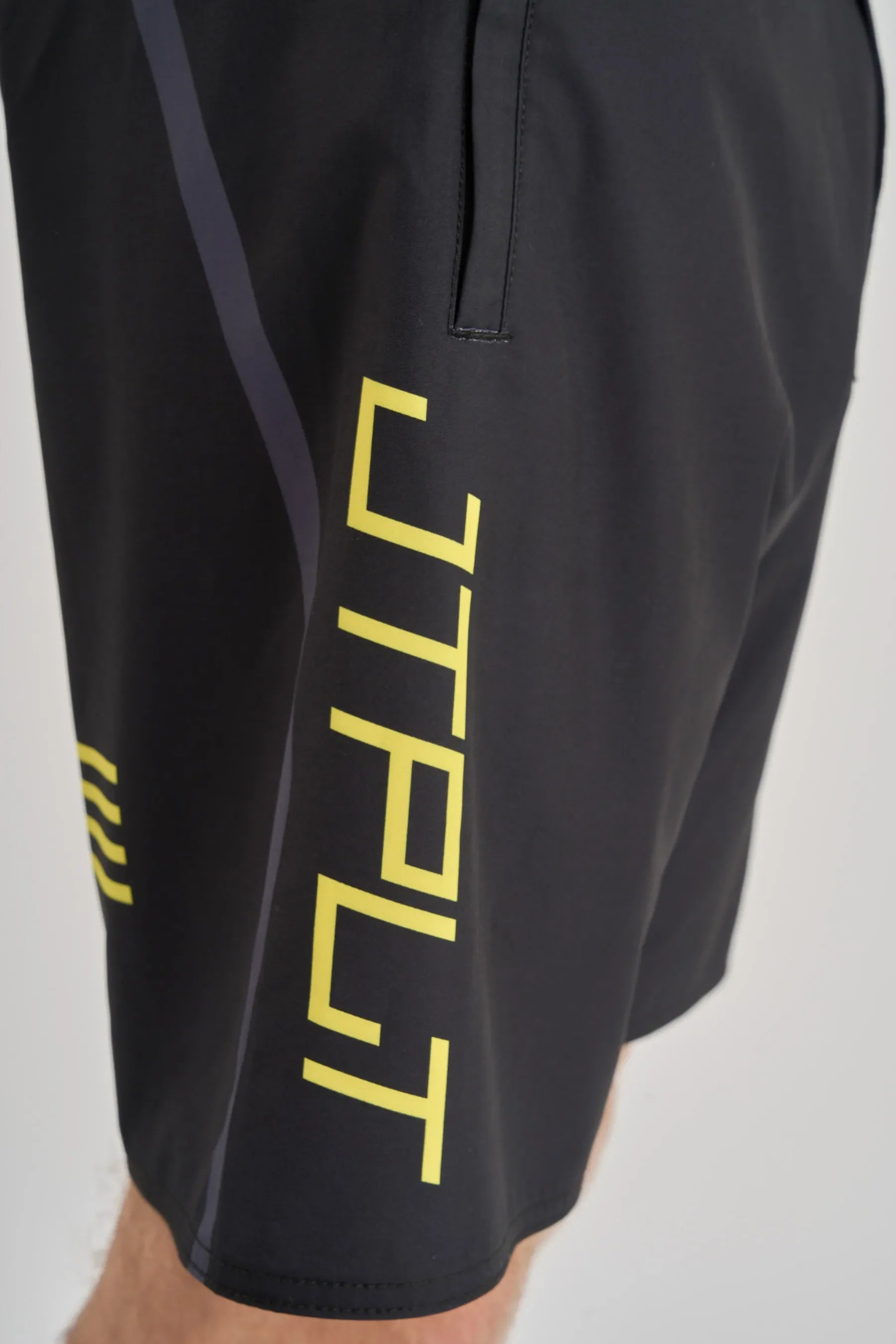 Black shorts with yellow 'JTPLT' branding on a light gray background