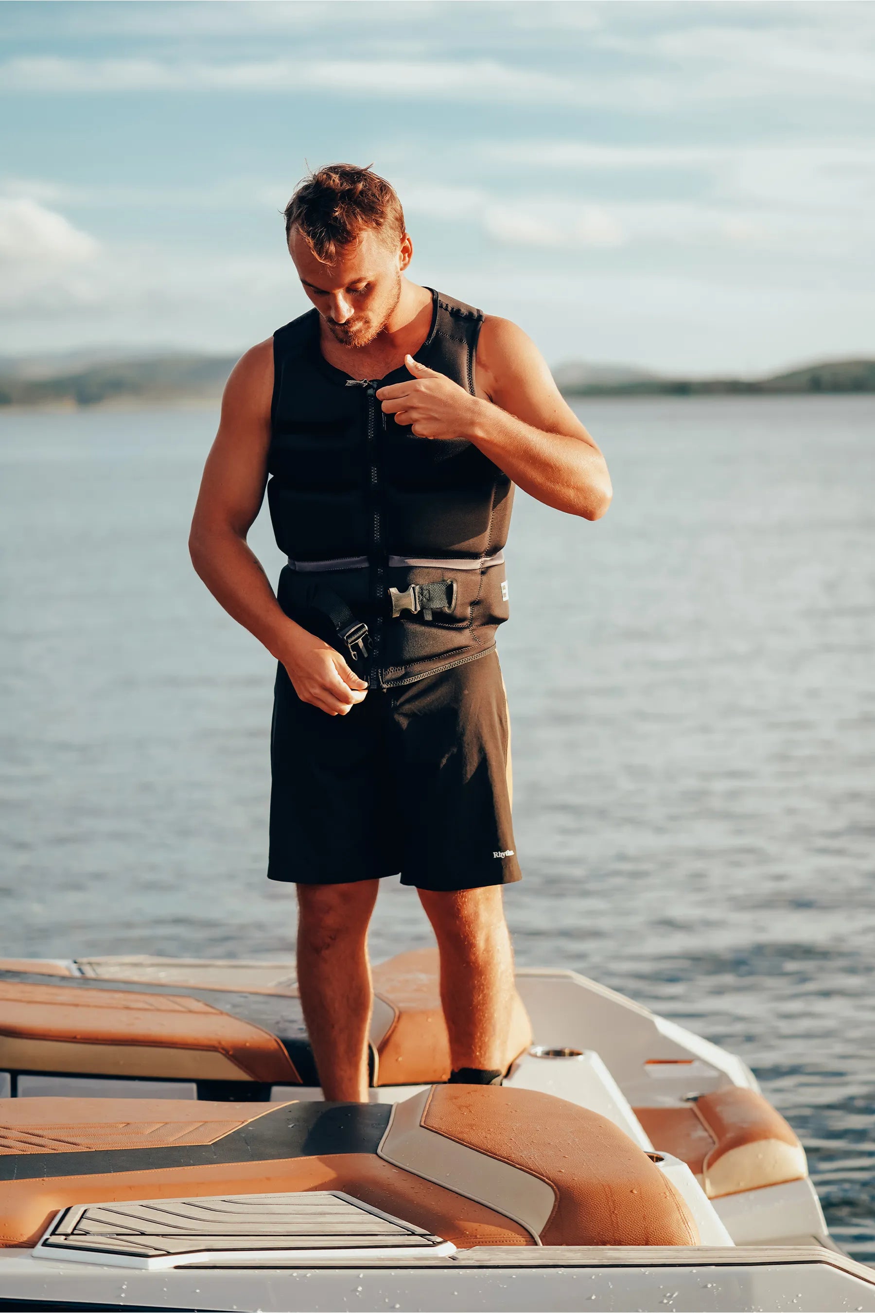 Man wearing Jetpilot C4 Mens Life Jacket - Cory Tuenissen Signature Series - Black on a boat with water and sky in the background