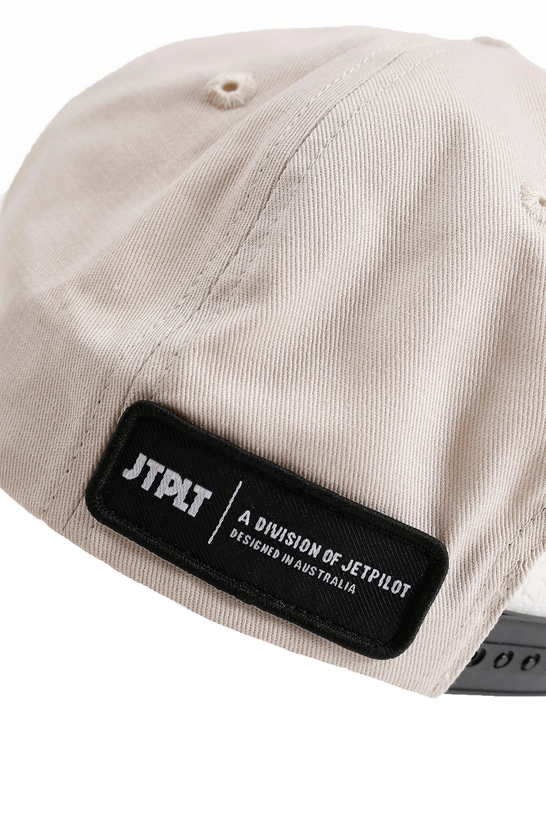 Beige cap with a black patch featuring 'JTPLT' branding on a white background