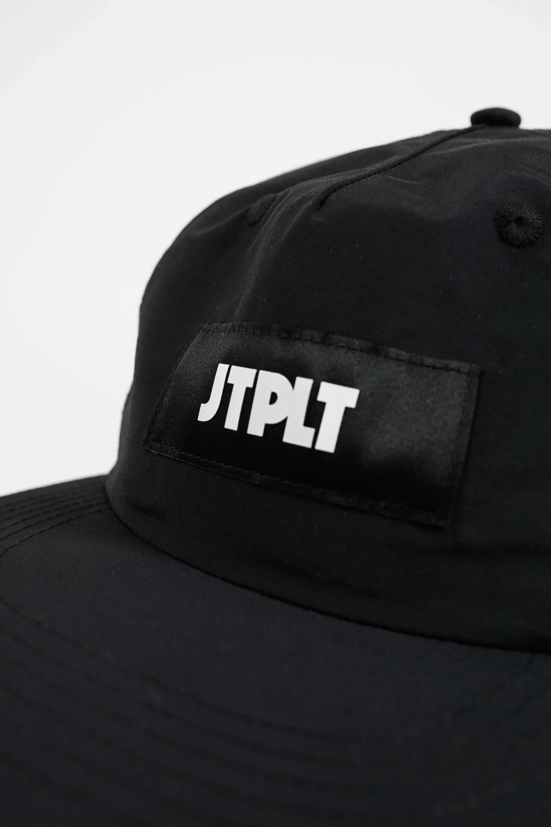 Black cap with 'JTPLT' logo on a light gray background