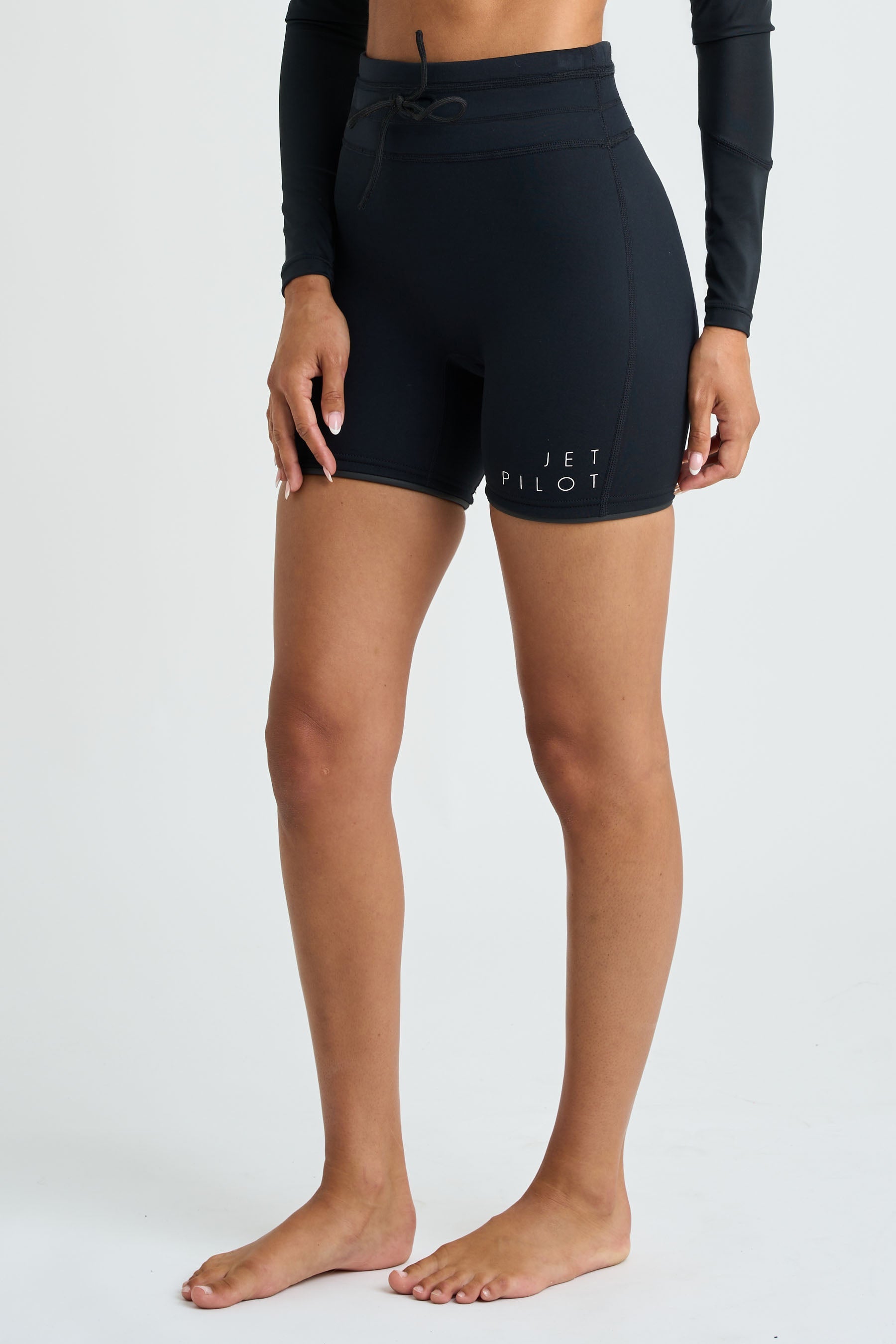 Person wearing black neoprene shorts with a visible Jetpilot logo on a white background