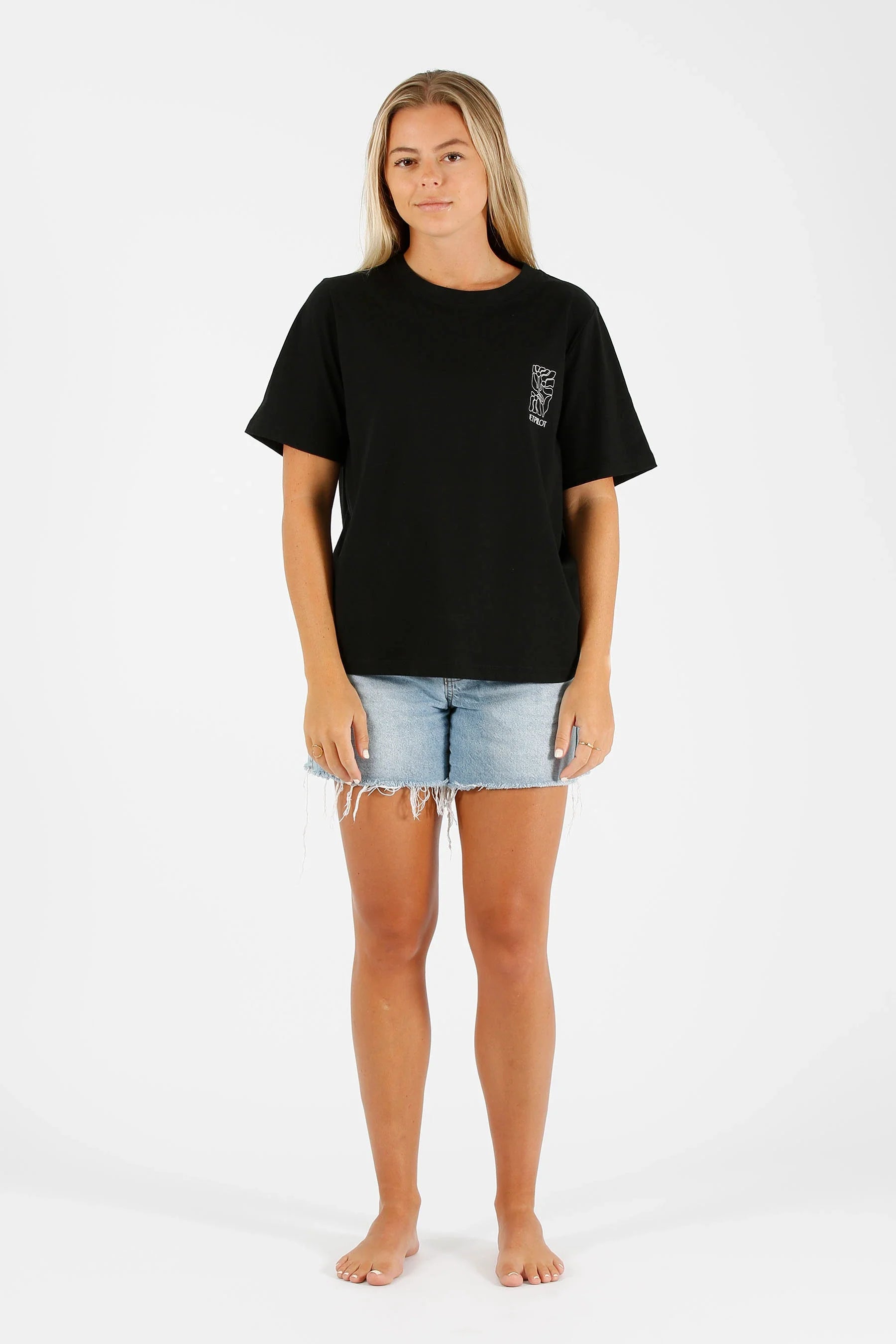 Woman wearing a black t-shirt and denim shorts on a white background